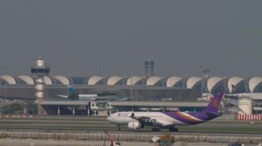 BANGKOK, THAILAND - Mart 01, 2023: THAI 'nin geniş gövdeli Airbus A330' u Suvarnabhumi Havalimanı 'na iniş ve dokunma, yan görüş. Uçak geliyor. Yolcu uçuşu pistte.