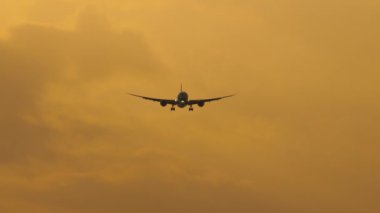 Jet airplane approaching to land in the sunset sky, long shot static. Tourism and travel concept