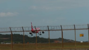 PHUKET, THAILAND - 22 Şubat 2023: Airbus A320 AirAsia iniş pisti, Phuket havaalanında fren yapıyor. Çitin arkasındaki uçağın görüntüsü. Spoiler verin. Seyahat kavramı