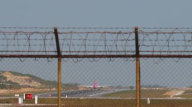 Jet uçağı kalkıyor, uzak plan, dikiz manzaralı. Yolcu uçağı kalkıyor. Havaalanı çitlerinden geçen pistin panoramik görüntüsü. Seyahat kavramı