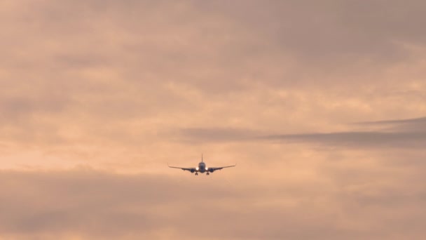 喷气式飞机接近着陆 客机在多云的落日天空中飞行 远距离拍摄 航空业的电影镜头 天空一片深红 — 图库视频影像