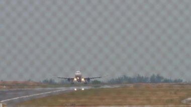 İniş için yaklaşan uzun menzilli bir jet uçağı. İniş yapan bir uçağın görüntüsü. Uçak geliyor. Haze havaalanında. Havaalanı çitlerinden bak.