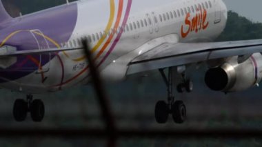 PHUKET, THAILAND - 25 HAZİRAN 2023: Yolcu uçağı A320-232, HS-TXB Thai Smile Airlines iniş pisti, yan görüş