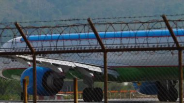 PHUKET, THAILAND - 27 HAZİRAN 2023: Airbus A321-253NX, Özbekistan Havayolları 'ndan UK32102, Phuket havaalanı pistinde taksicilik, orta çekim, yan görüş. Havaalanı çitlerinin dışındaki taksideki uçak.