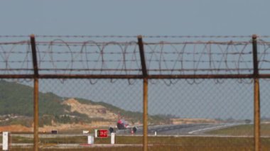 Jet uçağı kalkıyor, uzak plan, dikiz manzaralı. Yolcu uçağı kalkıyor. Havaalanı çitlerinden geçen pistin panoramik görüntüsü. Seyahat kavramı