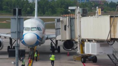 PHUKET, THAILAND - 28 Şubat 2023: Jet Airbus A320 Bangkok Havaalanı terminalinde. Kolu uçağa kenetliyorum. Uçak ve teleskopik iskele