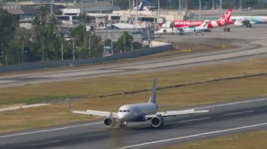 PHUKET, THAILAND - 23 Şubat 2023: Airbus A320, Phuket havaalanına indikten sonra VT-IPH frenleme, yan görüş, orta çekim. Uçağın görüntüsü geliyor. Spoiler hazır.