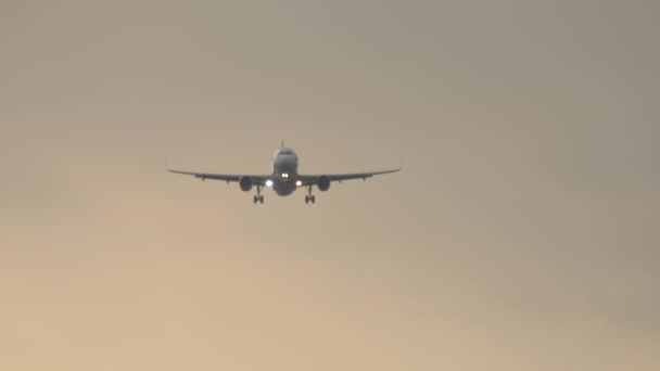 着陸に近づくジェット機の映像 旅客機は日没空 フロントビュー ロングショットで飛ぶ — ストック動画