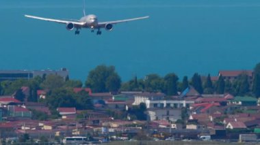 Uçak inişe geçiyor, yavaş çekim, ön görüş. Tanımlanamayan bir üniformayla gelen bir jet uçağı. Şehrin üzerinde geniş gövdeli uçaklar