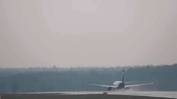 スピードアップし 濡れた滑走路で離陸するジェット機のリアビュー シャーシからのスプラッシュ — ストック動画