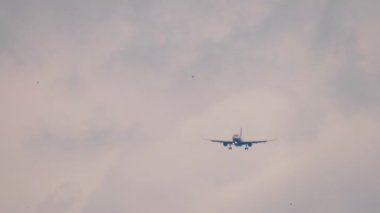 Alacakaranlık gökyüzüne iniş için yaklaşan uçak, uzak çekim, ön görüş. Uçan bir jet uçağının görüntüsü. Seyahat kavramı