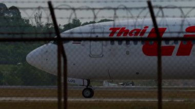 PHUKET, THAILAND - 25 HAZİRAN 2023: Phuket Havalimanı 'nda taksicilik yapan Tayland aslanı Boeing 737 yolcu uçağı. Havaalanı çitlerinin dışındaki uçak. Seyahat kavramı