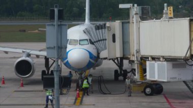 PHUKET, THAILAND - 28 Şubat 2023: Bangkok Air Airbus A320, Samui ahır Phuket havaalanı terminalinde. Teleskopik iskele bir uçağa kenetlendi. Uçuştan önce uçak hazırlığı.