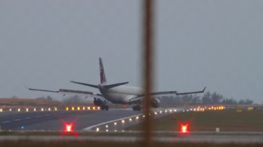 PHUKET, THAILAND - 16 Şubat 2023: Airbus A330, Katar Havayolları 'ndan A7-AEJ indikten sonra terminale iniyor. Spoiler verin. Pist iniş ışıklarıyla aydınlandı. Uçak geliyor.