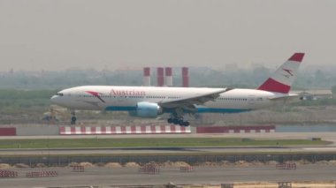 BANGKOK, THAILAND - Mart 01, 2023: Widebody Boeing 777, Avusturya Havayolları 'nın OE-LPC' si Suvarnabhumi Havaalanı BKK pistine iniyor ve iniş yapıyor. Yolcu uçağı geliyor, yan görünüm