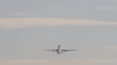 Tanımlanamayan üniformalı, dikiz manzaralı, uzun menzilli bir uçak. Uçak kalkıyor ve tırmanıyor. Kalkış uçuşu