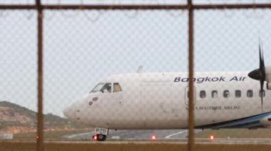 PHUKET, THAILAND - 16 Şubat 2023: Uzak çekim, Aeroflot 'tan Boeing 777 havalanıyor ve Phuket havaalanına tırmanıyor. ATR 72-600, Bangkok Havayolları 'nın HS-PZD' si piste çıkıyor. Ayrılmak için kuyruk