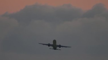 Gün batımında gökyüzüne tırmanan uçak silueti, dikiz manzarası. Uçağın kalkış görüntüleri. Uçak kalkıyor..