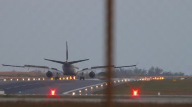PHUKET, THAILAND - 16 Şubat 2023: Airbus A330, Katar Havayolları 'ndan A7-AEJ. Spoiler verin. Pist iniş ışıklarıyla aydınlandı. Uçak geliyor.
