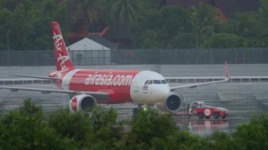PHUKET, THAILAND - NOVEMBER 28, 2019: Airbus A320-251N, HS-CBB Tayland Havaalanı 'nın Phuket Havaalanı' nda sağanak yağmur ve sağanak altında. Traktör ve havaalanı çalışanları