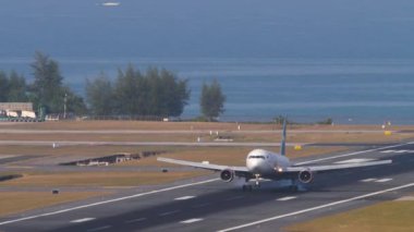 PHUKET, THAILAND - 23 Şubat 2023: pist üzerinde mavi denizin yanındaki uçak. Boeing 767, RA-73030 Azur Air 'in yavaşlaması Phuket havaalanına indikten sonra, ön görüş. Spoiler hazır.