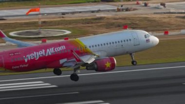 PHUKET, THAILAND - 11 Şubat 2023: Ticari uçak Airbus A320, Vietnam Jet Air iniş pistine HS-VKO, Phuket havaalanı, yan görüş dumanı ile piste dokunuyor