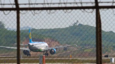 PHUKET, THAILAND - 27 HAZİRAN 2023: Airbus A321, Özbekistan Havayolları 'ndan UK32102 Phuket Havalimanı' ndan kalkmadan önce hızlanıyor. Yolcu uçağı, havaalanı çiti.