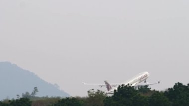 PHUKET, THAILAND - 26 Şubat 2023: Airbus A330, Katar Havayollarının A7-AEG kalkışı, Phuket havaalanına tırmanış, yan görüş. Uçuş kalkışı