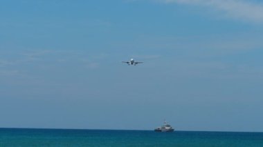 Gündüz bir kargo gemisinin üzerinde uçan uçak küresel lojistik, ulaşım ve tedarik zincirini sembolize ediyor.