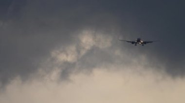 Uçak akşam inişe geçiyor. Bulutlu gün batımında iniş uçağı