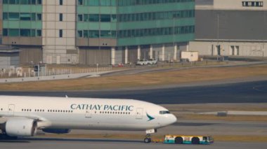 HONG KONG - 09 Kasım 2019: römorkör yolcu uçağı Boeing 777, B-HNK Hong Kong Havaalanı, yan görüş. Geniş gövdeli uçak çekiliyor.