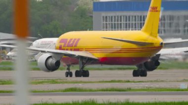 ALMATY, KAZAKHSTAN - 11 Mayıs 2024: Almaty havaalanında DHL 767 'nin kargo uçağı Boeing 767. Sarı üniformalı uçak.