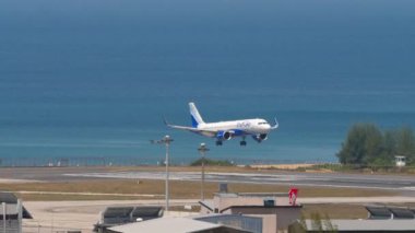 PHUKET, THAILAND - 20 Şubat 2023: Uzak çekim, Airbus A320, VT-IIP Indigo uçağı Phuket havaalanına iniyor. Yolcu uçağı geliyor. Uçak mavi denizin üzerinde uçar.