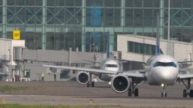 ALMATY, KAZAKHSTAN - 27 Haziran 2024: Airbus A321, Air Astana taksicilik EI-KGK, ön görüş. Embraer E190 'ın ardından Astana Havayolları' ndan El-KHE. Almaty Uluslararası Havaalanı, Kazakistan 'a trafik