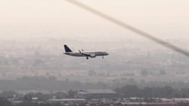 ALMATY, KAZAKHSTAN - 26 Haziran 2024: Airbus A320 Air Astana Almaty şehrine iniş yapmak üzeredir. Uçak uçuşu, yan görüş, uzak çekim.