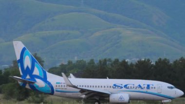 ALMATY, KAZAKHSTAN - 24 HAZİRAN 2024: uçak geliyor. Boeing 737, UP-B3725 inişten sonra fren yapıyor. Arka planda dağlar olan bir uçak. Seyahat kavramı