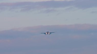 İniş yaparken farları yanan bilinmeyen bir uçağın uzak çekim görüntüsü.