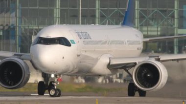 ALMATY, KAZAKHSTAN - 27 Haziran 2024: Ticari uçak Airbus A321, Air Astana 'dan EI-KGC Almaty Havaalanı' ndaki piste iniyor, yan görüş. Havaalanında uçak var.