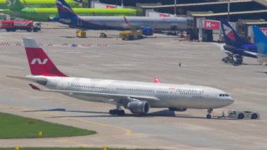 SOCHI, RUSSIA - 27 AĞUSTOS 2022: Airbus A330-223, RA-73328 Nordwind Havayolları çekici, yan görüş. Traktör uçağı piste itiyor.