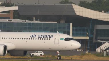 ALMATY, KAZAKHSTAN - 27 Haziran 2024: Air Astana Airbus A321 Almaty havaalanı terminaline yanaşıyor, yan görüş. Seyahat kavramı