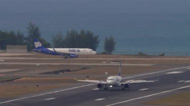 PHUKET, THAILAND - 13 Şubat 2023: inişten sonra uçak fren yapıyor, spoiler veriliyor. GoAir Airbus A320 piste iniyor. Havaalanı ve pist, arkada deniz.