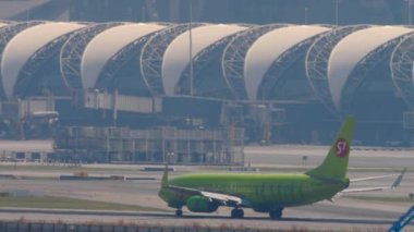 BANGKOK, THAILAND - Mart 01, 2023: Boeing 737, S7 Airlines 'dan RA-73668, Suvarnabhumi havaalanına iniş ve fren, yan görüş, uzak çekim. Uçak geliyor. Beneklenme