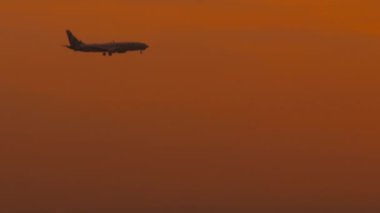 ALMATY, KAZAKHSTAN - 26 Haziran 2024: Boeing 737 SCAT Airlines jetinin günbatımına doğru uçan sinematik görüntüleri. Bir uçağın silueti, yuvarlak bir güneş ve kızıl bir gökyüzü.