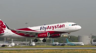 ALMATY, KAZAKHSTAN - 27 Haziran 2024: Airbus A320, FlyArystan 'dan EI-KBO iniş ve Almaty havaalanındaki piste iniş, yan görüş. Seyahat kavramı
