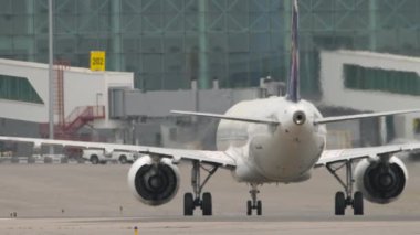 Yolcu uçağı piste çıkıyor, arka görüş. Hava trafiği, havaalanı. Arka planda büyük modern terminal. Seyahat kavramı