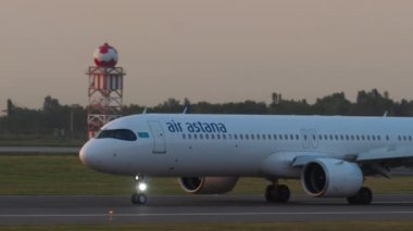 ALMATY, KAZAKHSTAN - 27 Temmuz 2024: yan görüş, Airbus A321, Air Astana EI-KGG yolcu uçağı gün batımında veya gün doğumunda pistte taksicilik yapıyor