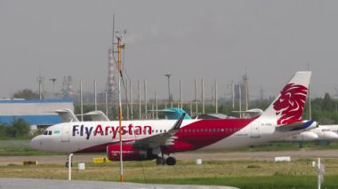 ALMATY, KAZAKHSTAN - 10 Mayıs 2024: Airbus A320, Fly Arystan 'dan EI-KBO Almaty havaalanında taksicilik, yan görüş. Taksiyoldaki bir uçağın görüntüsü. Önlük terminalinde sıra sıra bekleyen uçaklar.