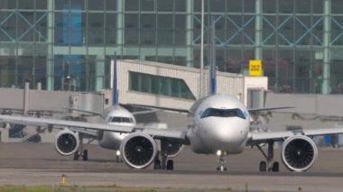 ALMATY, KAZAKHSTAN - 27 Haziran 2024: Airbus A321, Air Astana taksicilik EI-KGK, ön görüş. Embraer E190, Astana Havayolları 'ndan El-KHE. Terminalin önünde iki uçak.