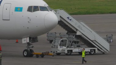 ALMATY, KAZAKHSTAN - 10 Mayıs 2024: merdivenli beyaz yolcu uçağı. Boeing 767, Air Astana 'nın El-KEC' si. Uçağa binen yolcular.