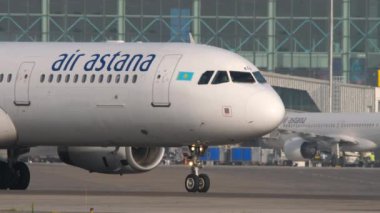 ALMATY, KAZAKHSTAN - 27 Haziran 2024: Airbus A321, Air Astana EI-KDA Almaty Havaalanı pistinde. Uçak kalkış için hazır. Önlük, havaalanı terminali